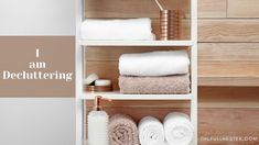 towels and toiletries on shelves in a bathroom with text that reads, i am decluttering