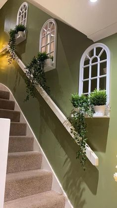 the stairs are painted green with white windows and potted plants on each window sill