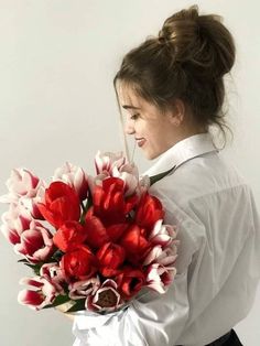 a woman holding a bouquet of red and white tulips