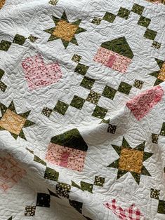 a close up of a quilt on a bed with white and green fabric, which has an arrow design