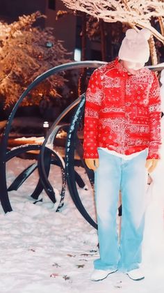 a man standing in the snow with his back to the camera, wearing blue jeans and a red shirt