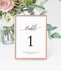 a table number card with flowers and greenery