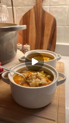 two bowls filled with soup on top of a wooden cutting board next to a pot