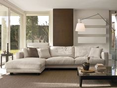 a living room with a sectional couch and coffee table in front of large windows that look out onto the backyard