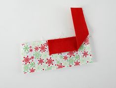 a piece of fabric with red and green snowflakes on it, next to a pair of scissors