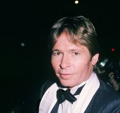 a man in a tuxedo and bow tie standing next to a cameraman