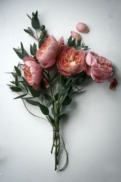 a bunch of pink flowers sitting on top of a white table next to some green leaves