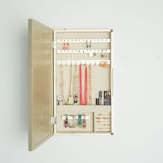 an open cabinet with necklaces, bracelets and other items in it on a white background