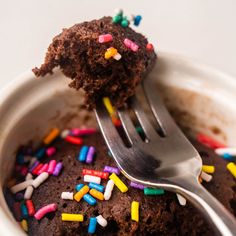 a fork is stuck into a chocolate cupcake with sprinkles