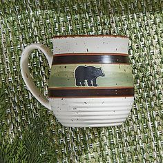 a brown and white coffee cup with a bear on the side sitting on a green tablecloth