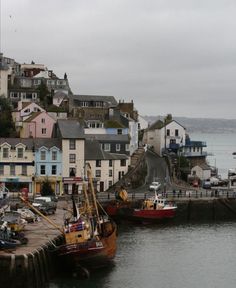 two boats are docked in the water next to some buildings and a dock with houses on it