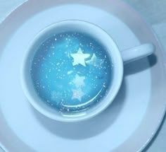 a white plate topped with a blue cup filled with liquid and stars on top of it