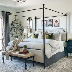 a bedroom with four poster bed and white walls