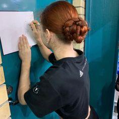 a woman with red hair is working on a piece of paper in front of a blue wall