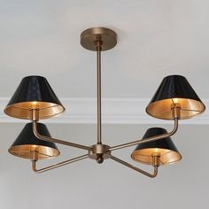 a chandelier with three black lamps hanging from it's sides and two gold shades