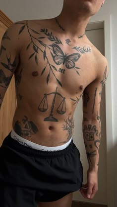 a man with many tattoos on his body and chest standing in front of a door