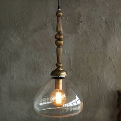 a clear glass light hanging from a ceiling fixture in a room with concrete walls and flooring