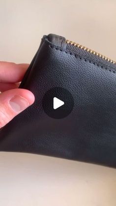 a hand holding a black leather wallet with a white arrow on the front and bottom