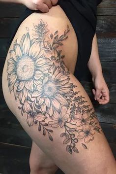 a woman's thigh with sunflowers and leaves on it