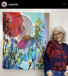 an older woman standing next to a colorful painting