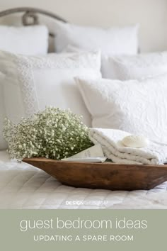 a bed with white sheets and pillows on it, next to a basket filled with baby's breath flowers