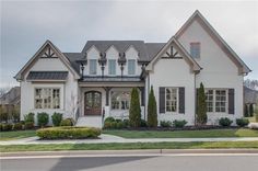 a large white house with lots of windows and bushes on the side of the road