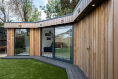 a wooden building with sliding glass doors on the outside and grass in the front yard