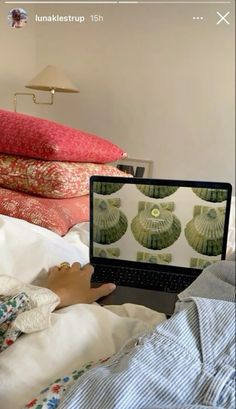 a person laying in bed looking at a laptop on their lap top with the screen turned off