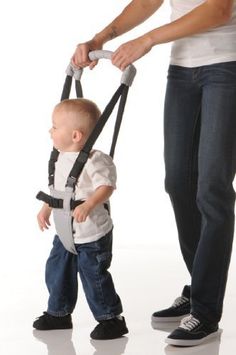 a woman holding onto a child's harness while standing next to him