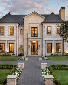 a large white house with lots of windows and plants in front of the entrance to it