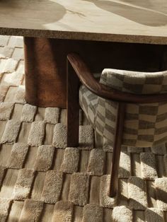 a chair sitting under a wooden table with a checkered seat cover on it's back