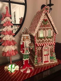 a gingerbread house is decorated with candy canes and other holiday decorations on a table in front of a mirror