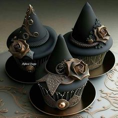 three cupcakes decorated with black and gold decorations on top of each other,