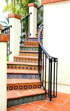 a set of stairs with decorative tiles and wrought iron handrails