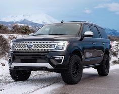 a black ford expedition vehicle driving down a snowy road