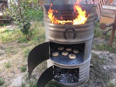 a large metal barrel with some food cooking on it's side in the yard