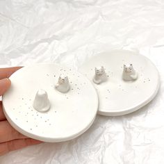 two white ceramic plates with cats on them, one being held by a person's hand