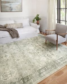 a living room with a couch, chair and rug in front of a large window