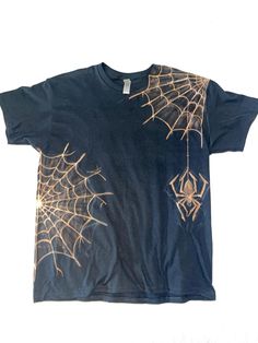 a black t - shirt with gold spider webs on it