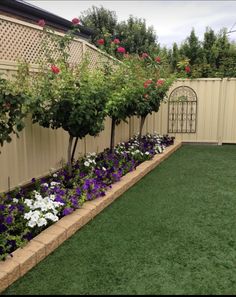 a backyard with artificial grass and flowers in it