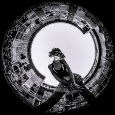 a woman with curly hair standing in front of a circular window