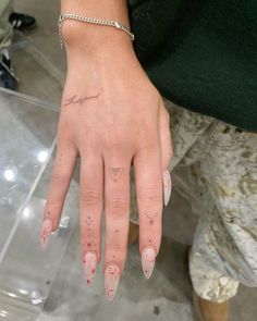 a woman's hand with pink and white nail polish on her left thumb, wearing a bracelet