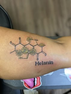 a tattoo with the name melanin written on it's arm and flowers