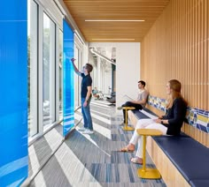 three people sitting on benches in an office building