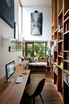 a home office with bookshelves, desk and computer on the table in front of large windows