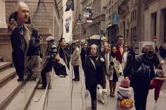 a group of people walking down a street next to tall buildings