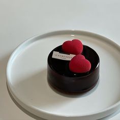 there is a small chocolate cake with two red hearts on the top and a name tag