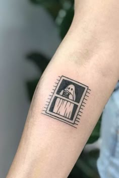 a person's arm with a dog in a window tattoo on the left forearm