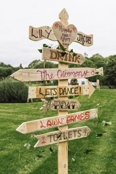 a wooden sign with many different signs attached to it's sides in the grass