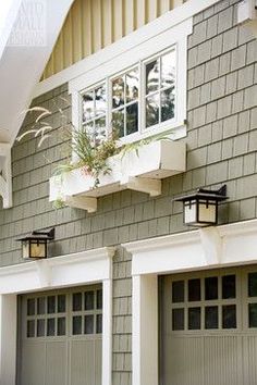 two garage doors are open in front of a gray house with white trim and windows